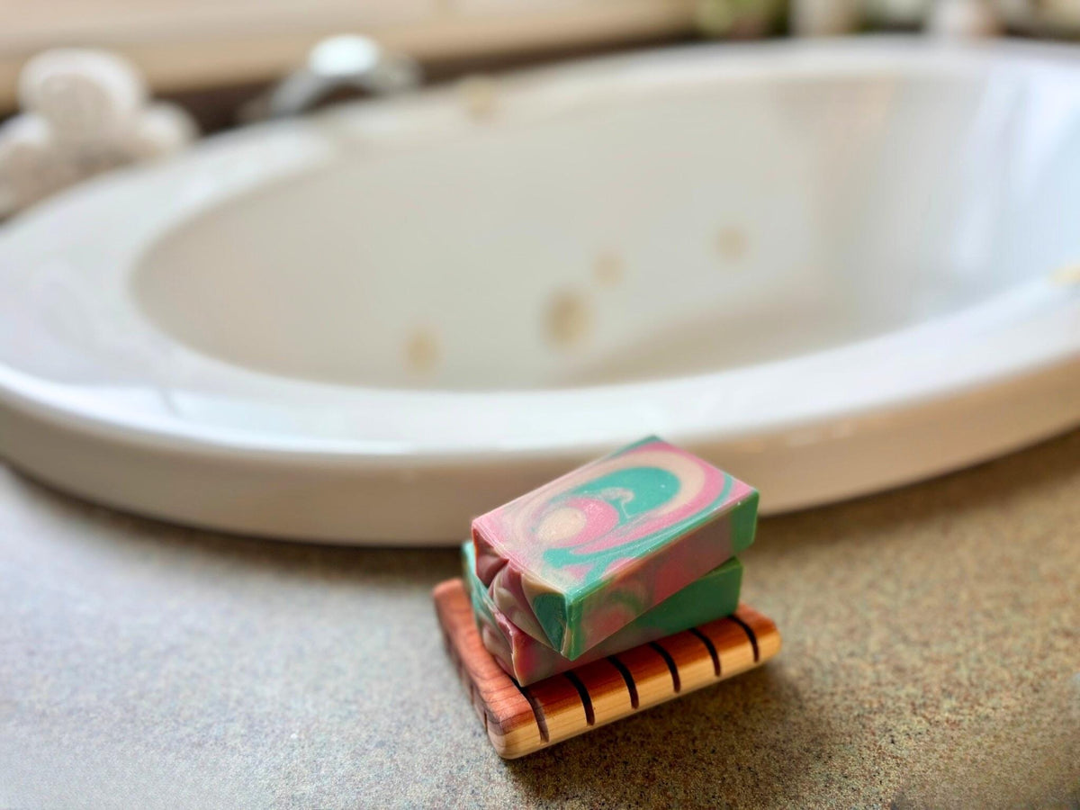 Colorful soap on a wooden soap dish with a bathtub in the background