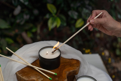 Person lighting a candle with wooden matches on a wooden board.