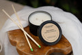 Palo Santo candle and match sticks on a wooden coaster with a white cloth background