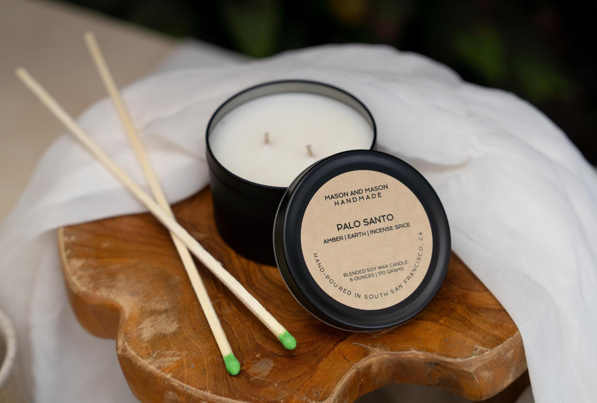 Palo Santo candle and match sticks on a wooden coaster with a white cloth background